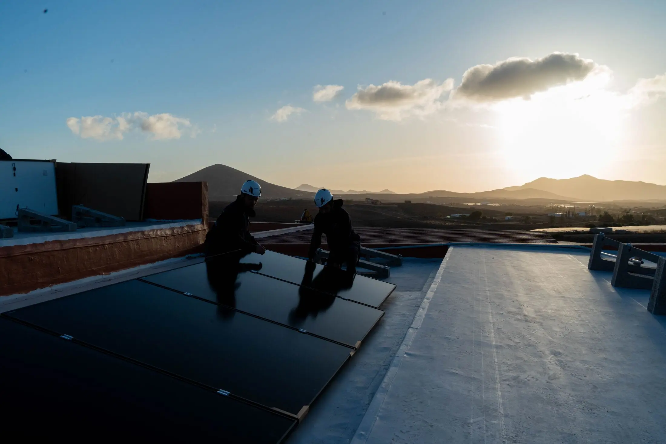 Instaladores de Canarias Autosostenible colocando paneles solares al atardecer en un tejado de Fuerteventura