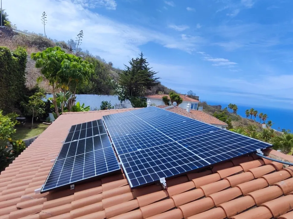 Placas solares en un tejado de tejas con vistas al mar